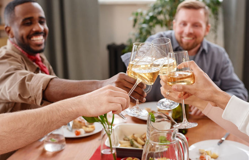 A group of friends enjoying a celebratory toast with champagne during a festive dinner indoors.