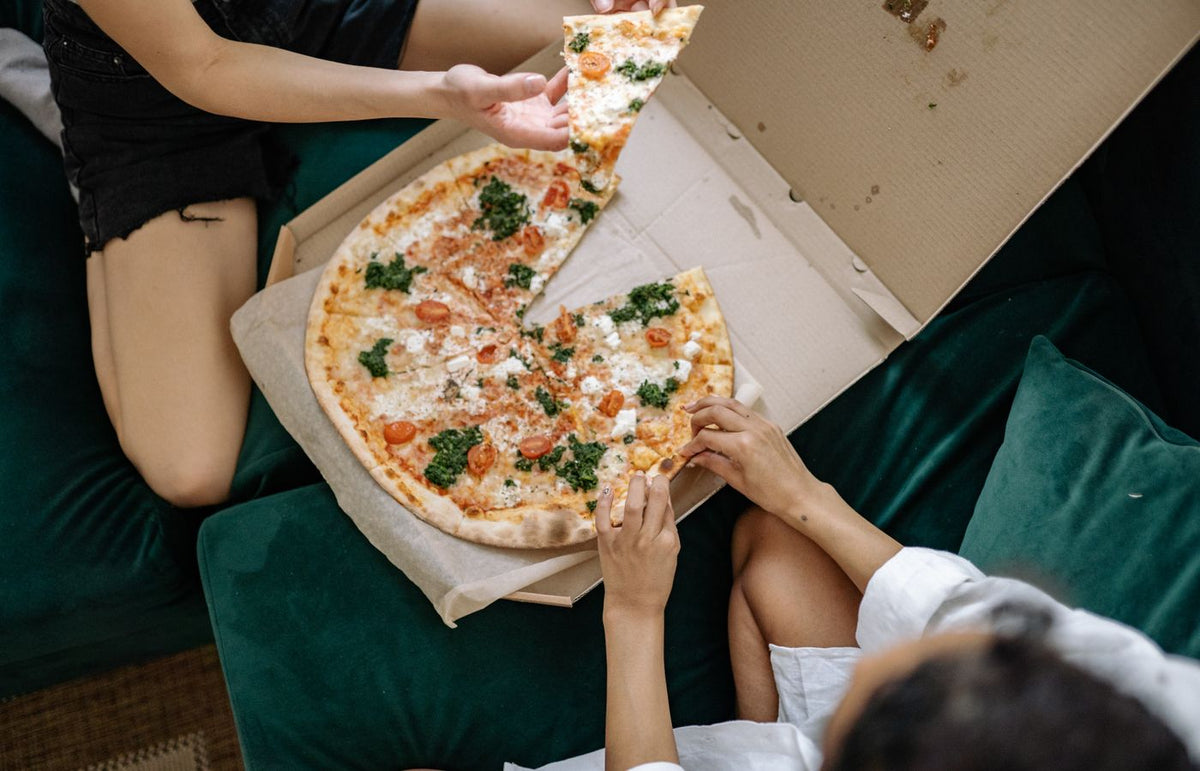 Top view of friends sharing a large pizza at home, capturing a casual dining moment.