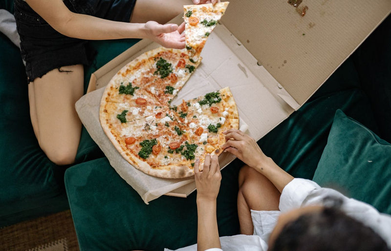 Top view of friends sharing a large pizza at home, capturing a casual dining moment.