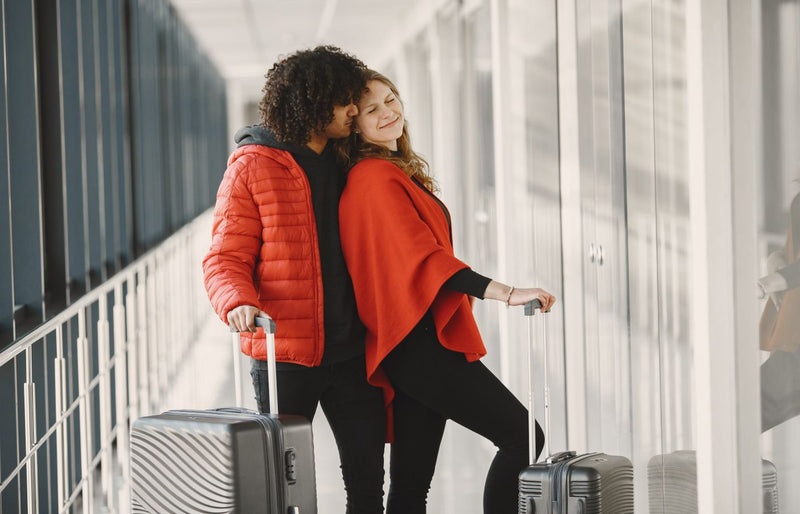 Smiling couple standing with luggage in an airport corridor, enjoying their journey.