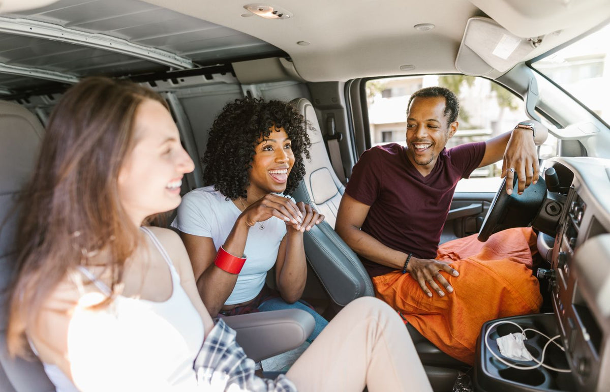 Group of friends laughing and enjoying a road trip inside a van. Perfect for travel and lifestyle themed projects.