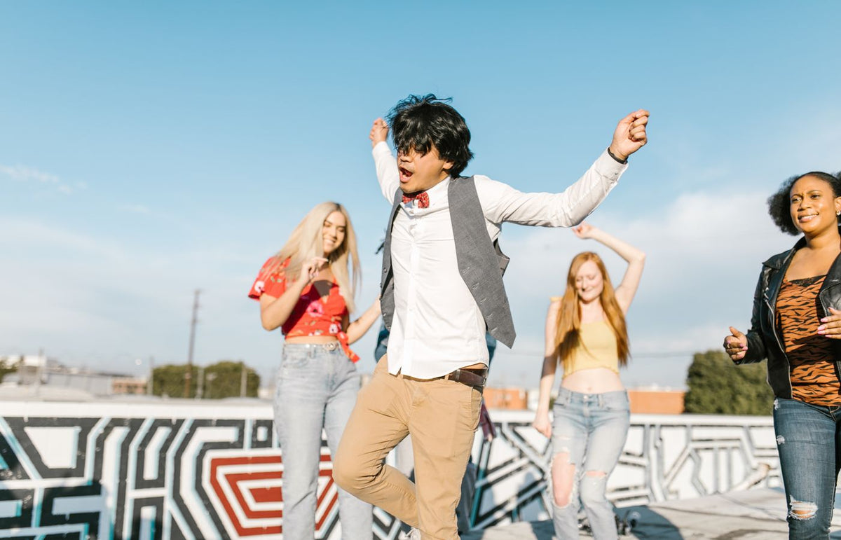 Young adults enjoying a vibrant rooftop dance party under a clear blue sky.