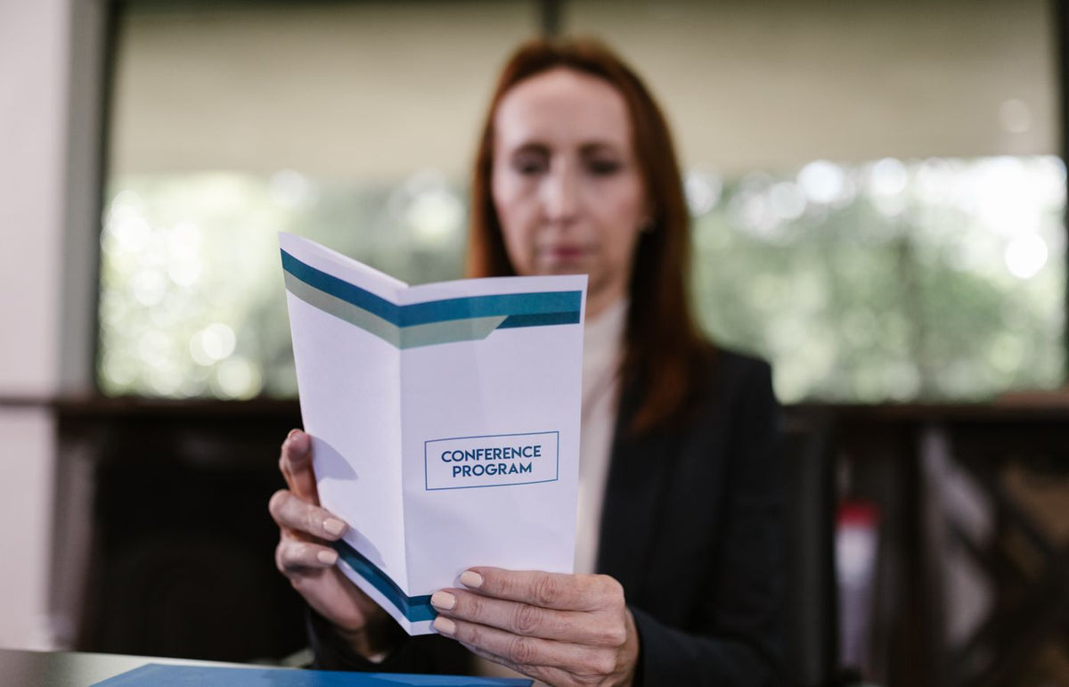 Businesswoman examining the conference program in a meeting room setting.