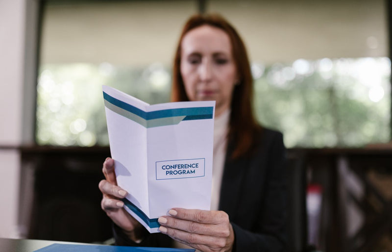 Businesswoman examining the conference program in a meeting room setting.