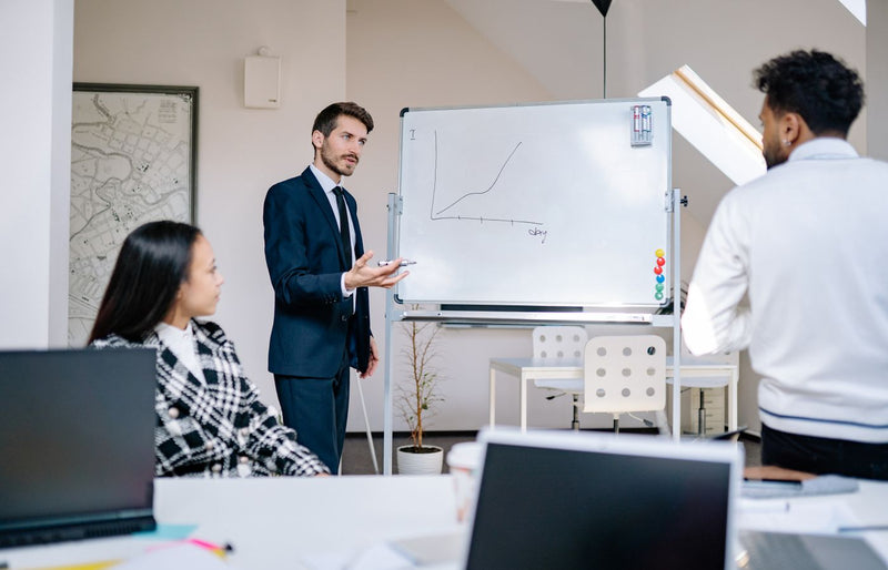 Business team in office presenting growth graph on a whiteboard for strategy discussion and teamwork insights.