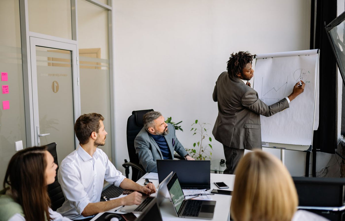 A diverse team in a modern office engaged in a strategic business meeting led by a presenter.