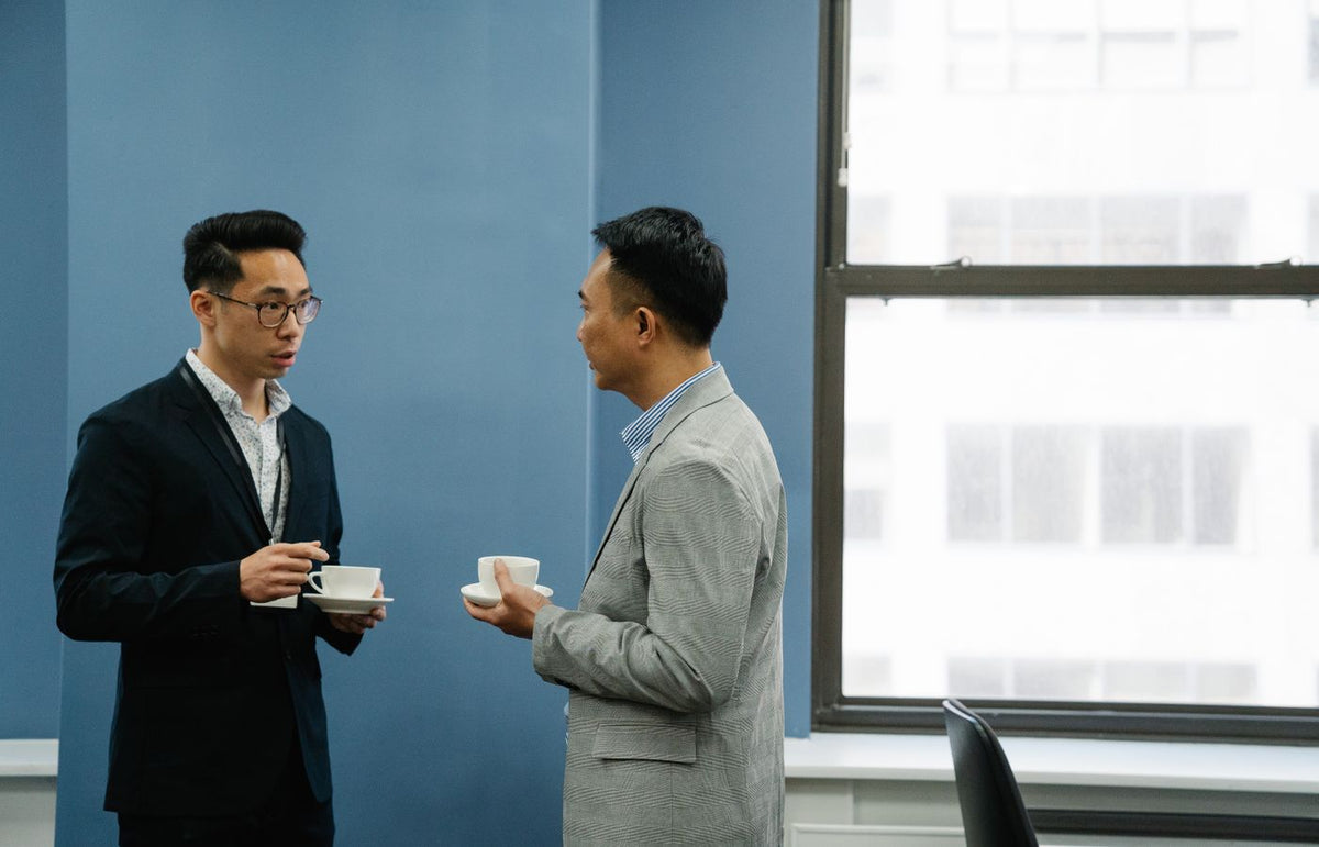 Two professionals engaged in a friendly discussion over coffee in an office setting.
