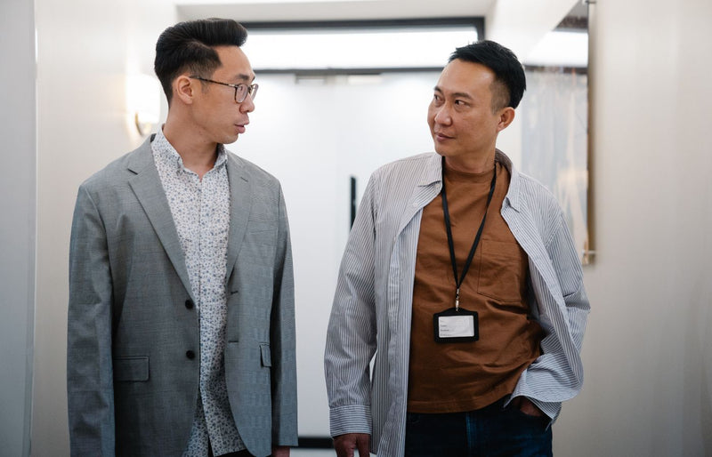 Two professional men conversing in a well-lit corridor, showcasing teamwork and cooperation.