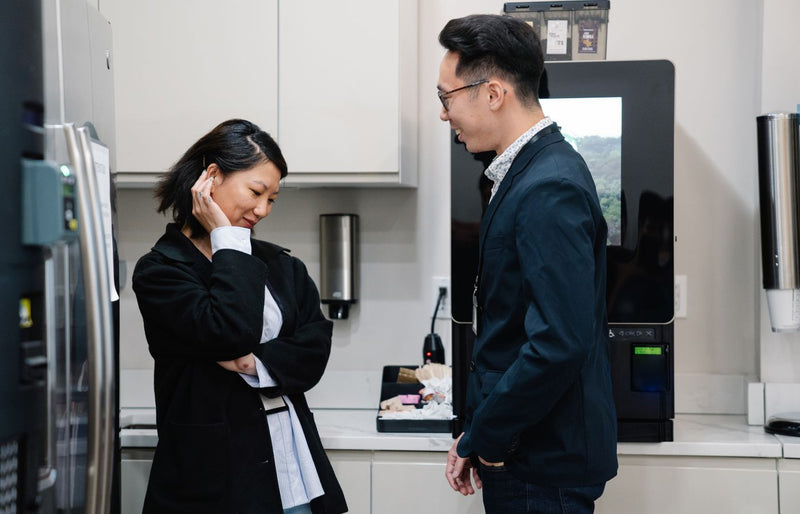 A candid moment of a man and woman talking in a stylish kitchen environment.