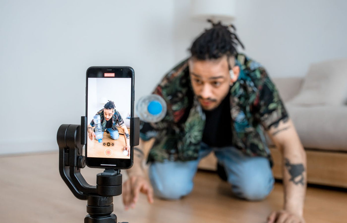 Man filming creative content with smartphone on gimbal indoors.