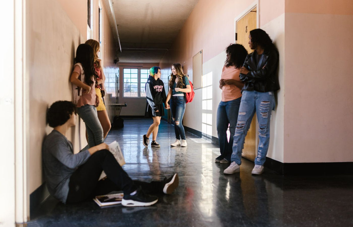 Students interact and relax between classes in a school's bright hallway.