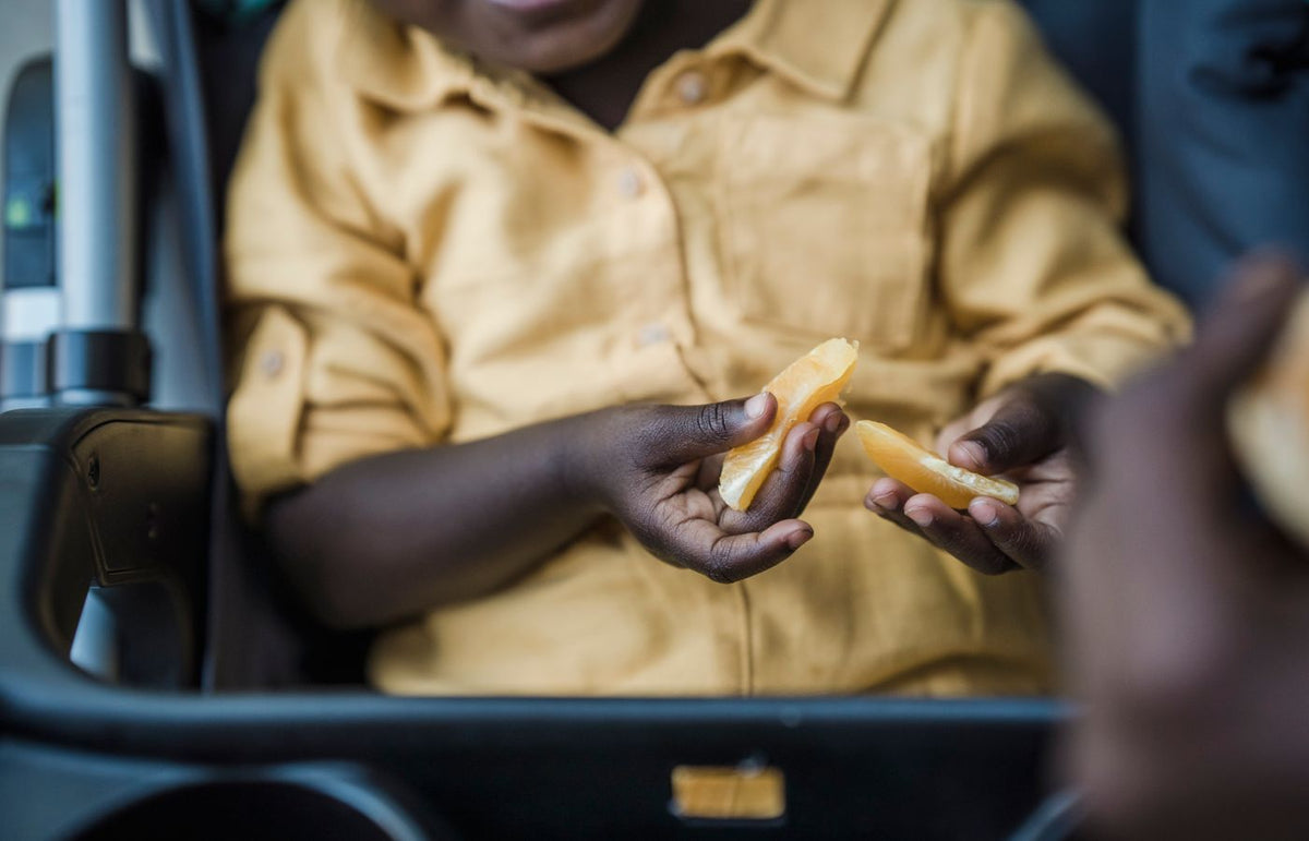 Close-up of a child's hands holding orange slices, highlighting the joy of simple snacks.