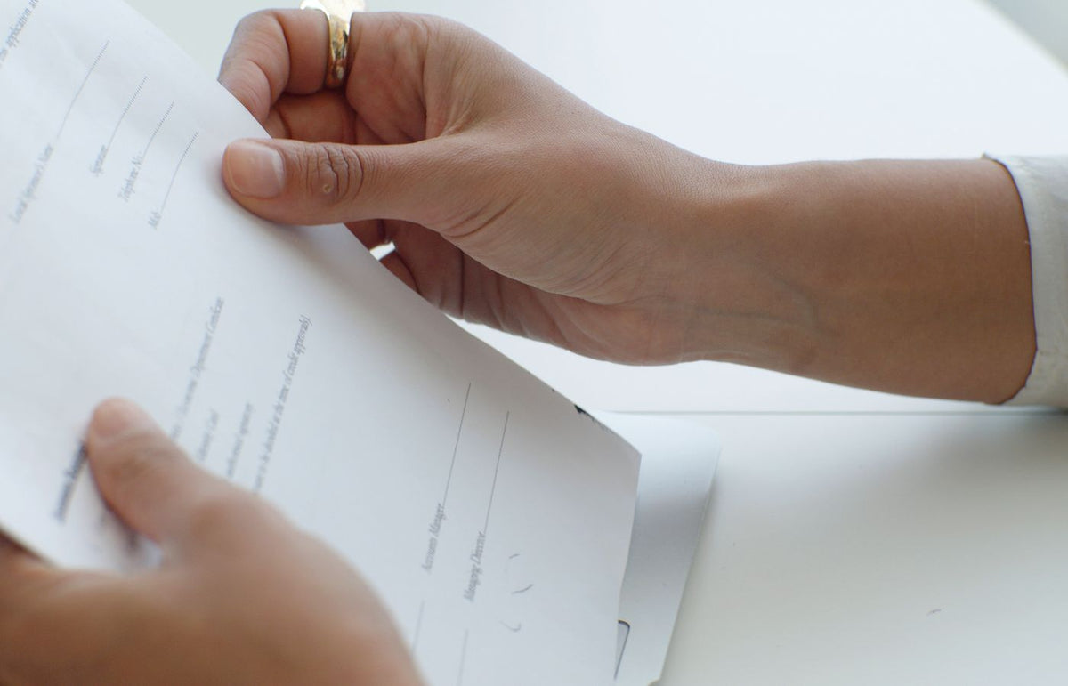 Close-up view of hands holding a document over a keyboard in an office.