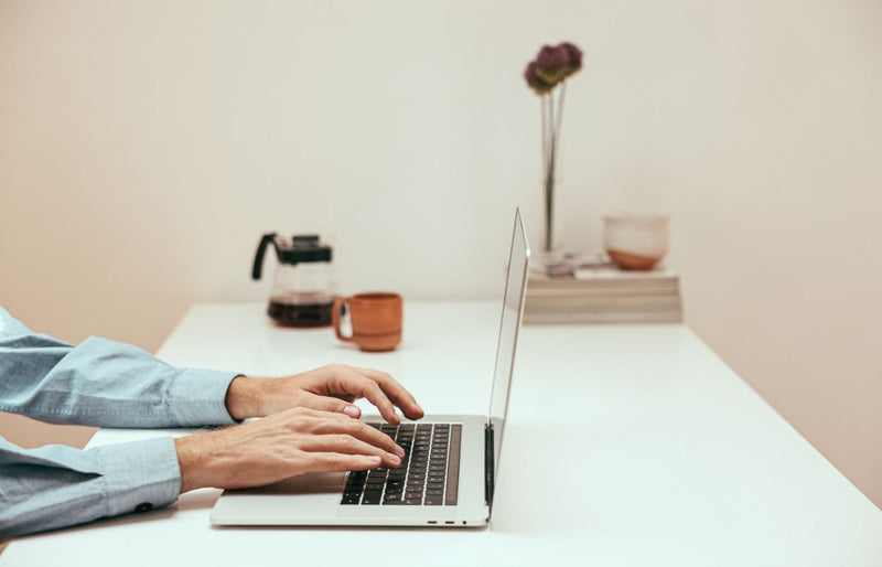 Hands typing on a laptop in a stylish home office, symbolizing modern remote work lifestyle.
