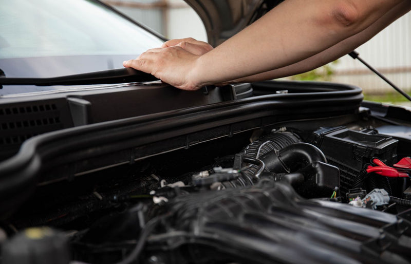 Close-up of hands working on car engine. Detailed view of automotive repair.