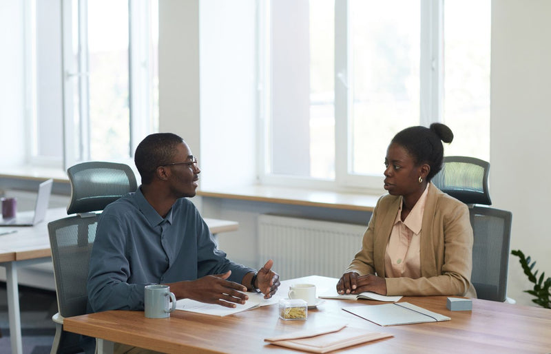 Two colleagues having a business conversation in a modern office setting.