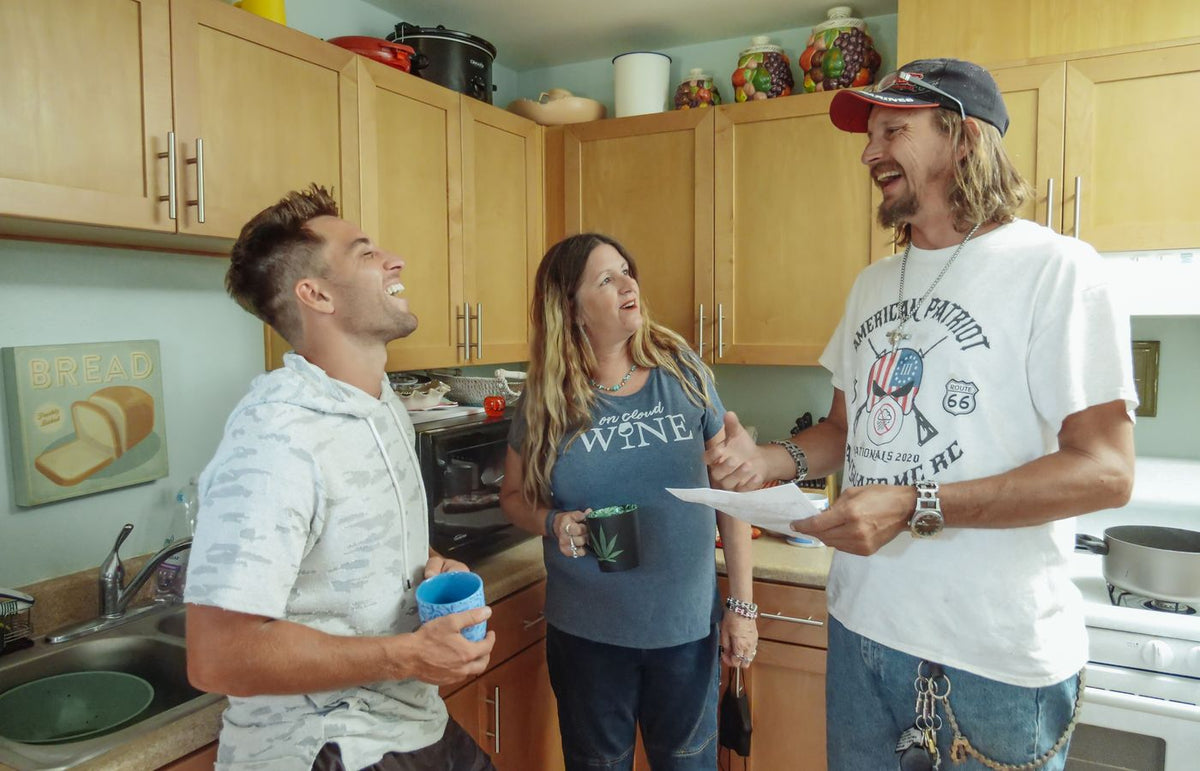 Three adults enjoy a lively conversation in a cozy kitchen setting.