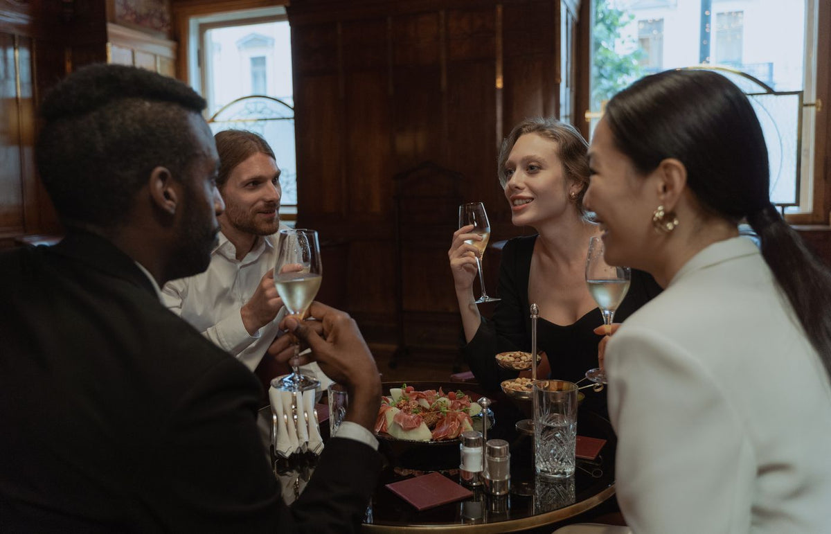 A diverse group of friends enjoying drinks and dinner in a stylish restaurant setting.