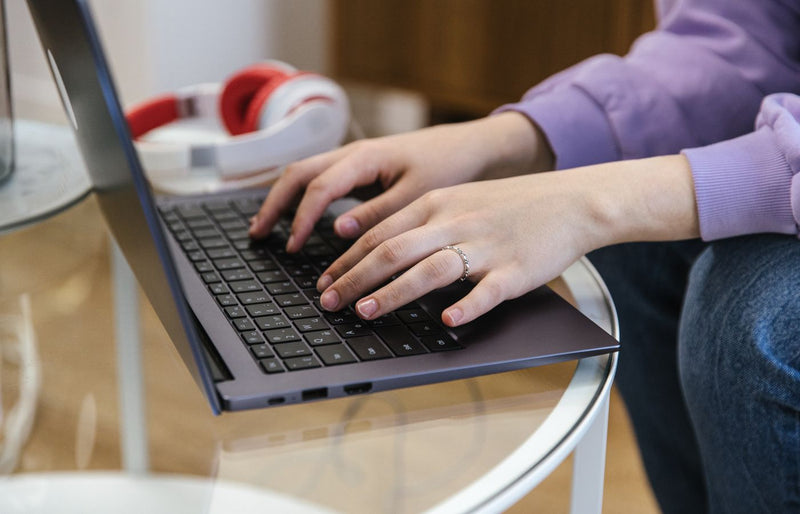 Close-up view of hands typing on a laptop indoors, showcasing technology and productivity.