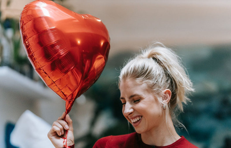 A joyful woman holding a heart-shaped balloon, adding happiness and warmth to the scene.