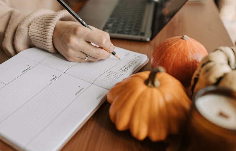 A cozy workspace with a planner, pumpkins, and a laptop, capturing the essence of autumn planning.